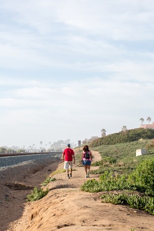 A couple walks along the east side of tracks in Cardiff on Feb. 14. The area is a possible location for a portion of the Coastal Rail Trail. (Photo by Jen Acosta)