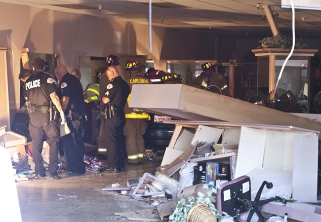 Firefighters work to extricate a woman pinned by a BMW that was driven into the Country Club Salon, in Oceanside Photo: Steve Marcotte/OsideNews