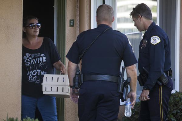 Oceanside Police motor-officers  Justin Willms and Duane Schott escort a resident to get her African Grey Parrot