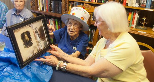 Agnes McKee looks at a photo with Helen Huffman that was  taken of her in 1927 
