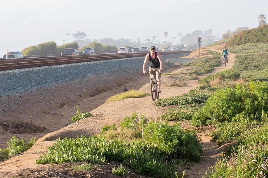 Bicycle riders use a path alongside the rail line in Cardiff on Feb. 14. The area is a possible route for the Coastal Rail Trail. (Photo by Jen Acosta)