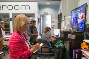 Teri Leon, program manager for Carlsbad High School’s television program (CHSTV), takes notes of a rehearsal broadcast Oct. 13. Leon uses the notes to coach the anchors of the award-winning, student-run news program. (Photo by Troy Orem)