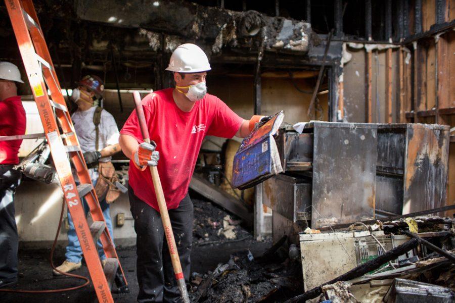 Austin Albrecht removes a charred book from the Oak Crest Middle School administration building in Encinitas on Oct. 31. The building was destroyed by fire Oct. 29. (Photo by Cam Buker)