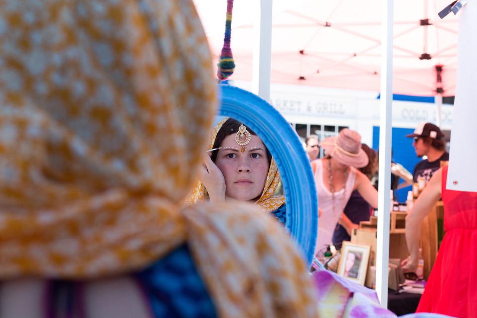 Genevieve Ruddock applies face paint called Gopi Dots during The Encinitas Street Fair on April 30.   She recently returned from an eight-month India trip teaching children art. Since she started traveling extensively to India, she has completed various art projects with the children from tie-dye to mural painting. (Photo by Cam Buker)