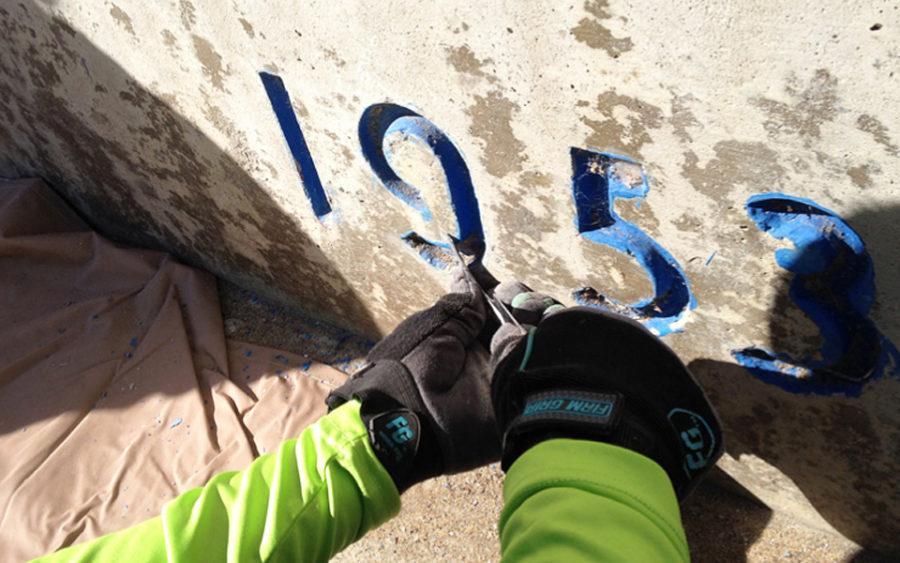 In this photo from an Encinitas Arts, Culture and Ecology Alliance impact report, a volunteer works on the former Pacific View school site's year stamp on an entrance wall at the Encinitas campus. (Encinitas Arts, Culture and Ecology Alliance photo)