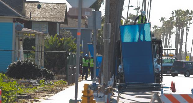 Workers install fencing around two block in downtown as construction begins on two resort hotels.