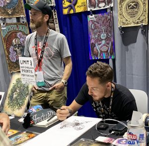Carlsbad artist N.C. Winters draws a sketch for fan Susie Lum of La Mirada at his San Diego Comic-Con booth as assistant Seth Stewart (left) talks to visitors. The convention ran July 18-21 in downtown San Diego. (Photo by Meghan Lanigan)
