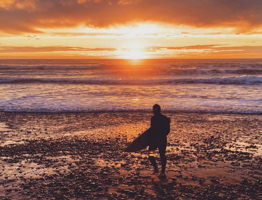 A surfer walks along Moonlight Beach in Encinitas. (Photo by Trevor Gerzen, Unsplash)