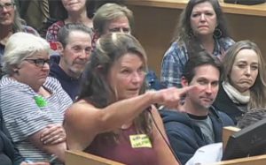 Cardiff resident Julie Thunder points toward the Encinitas city seal on the wall of the City Council chambers on Jan. 22 during the announcement of her run for mayor. (Encinitas city video feed)