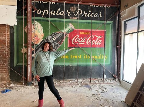 Eileen Burke, owner of Queen Eileen’s Gift Baskets in downtown Encinitas, shows off a 1950s-era mural uncovered in her shop during remodeling in February. (Courtesy photo)