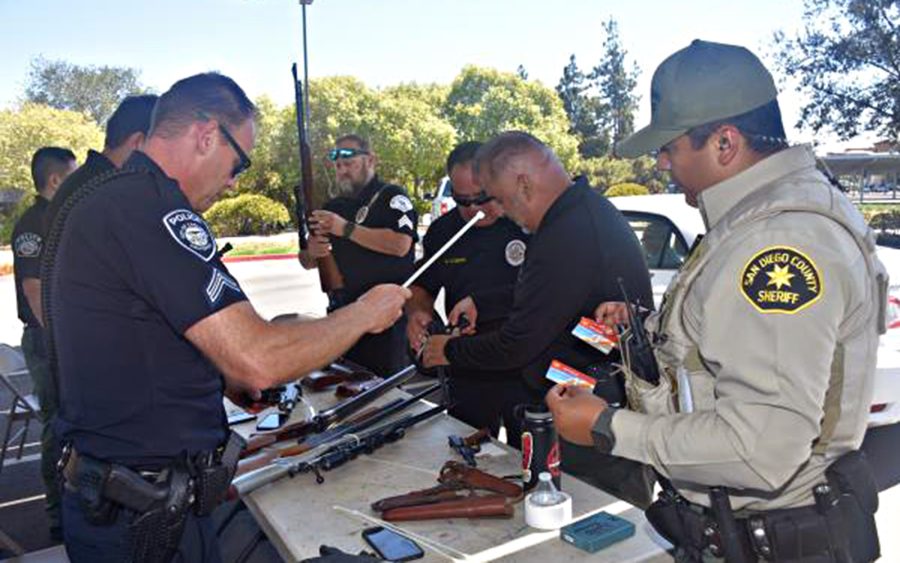 Authorities from the San Diego Sheriff’s Department and coastal North County police departments examine weapons turned in during a Guns for Gift Cards event in Vista the weekend of Aug. 27. (Sheriff’s Department photo)