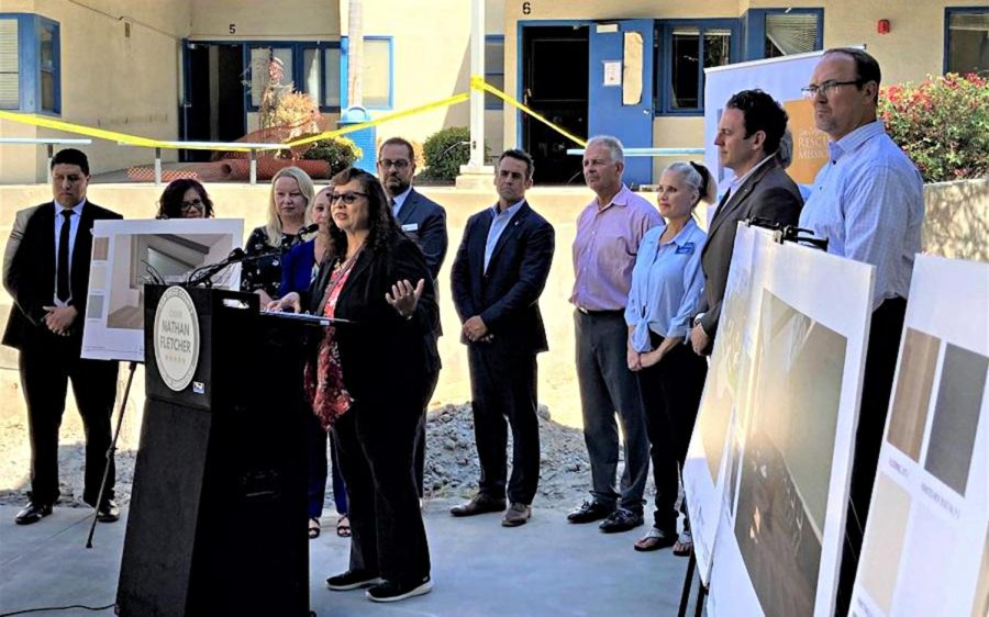 Oceanside Mayor Esther Sanchez speaks about a $3.3 million homeless shelter grant at a news conference Sept. 21 at the facility site. She's joined by (left to right) Salvador Roman, management analyst/homeless services; Leilani Hines, Housing and Neighborhood Services director; county staff; City Manager Jonathan Borrego; Deputy Mayor Ryan Keim; Councilman Peter Weiss; Councilwoman Kori Jensen; county Supervisors Jim Desmond and Nathan Fletcher; and San Diego Rescue Mission President and CEO Donnie Dee. (Oceanside city photo)