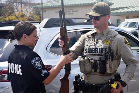 A Carlsbad police officer and San Diego County sheriff’s deputy handle a firearm collected during a Gun Safety Event held March 25 in San Marcos. (San Diego County Sheriff’s Department photo)