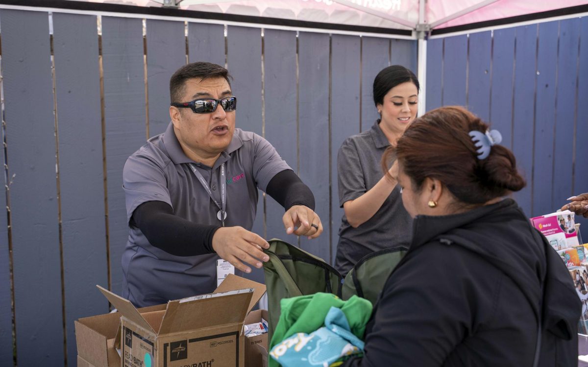 TrueCare representatives hand out shirts, socks, hats and backpacks to those in need during a Healthcare for the Homeless event held in partnership with Brother Benno’s in Oceanside on Aug. 7. (Courtesy photo by Guillermo Ramirez)